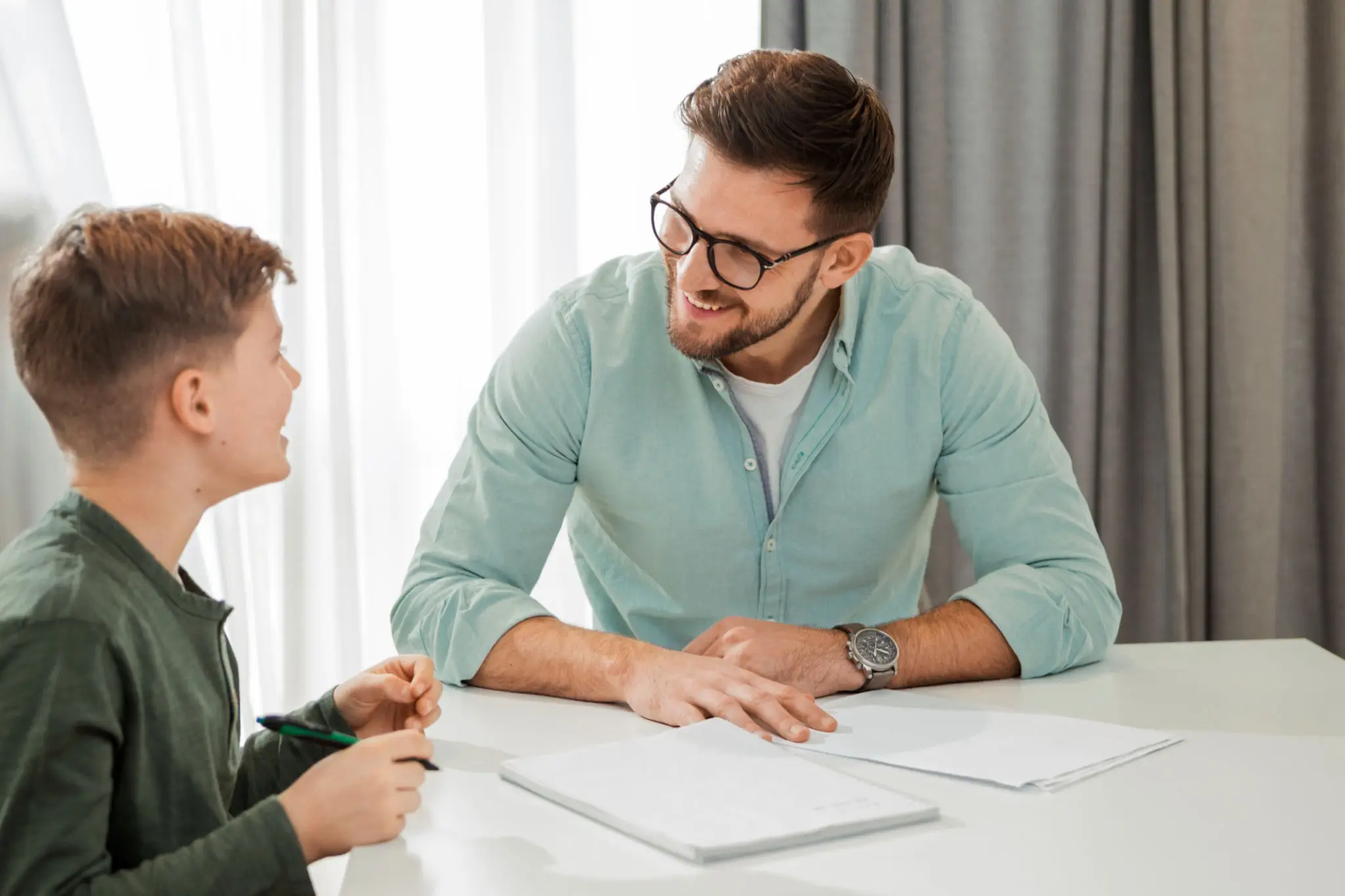 Man and woman discussing work at a desk with a laptop and documents.